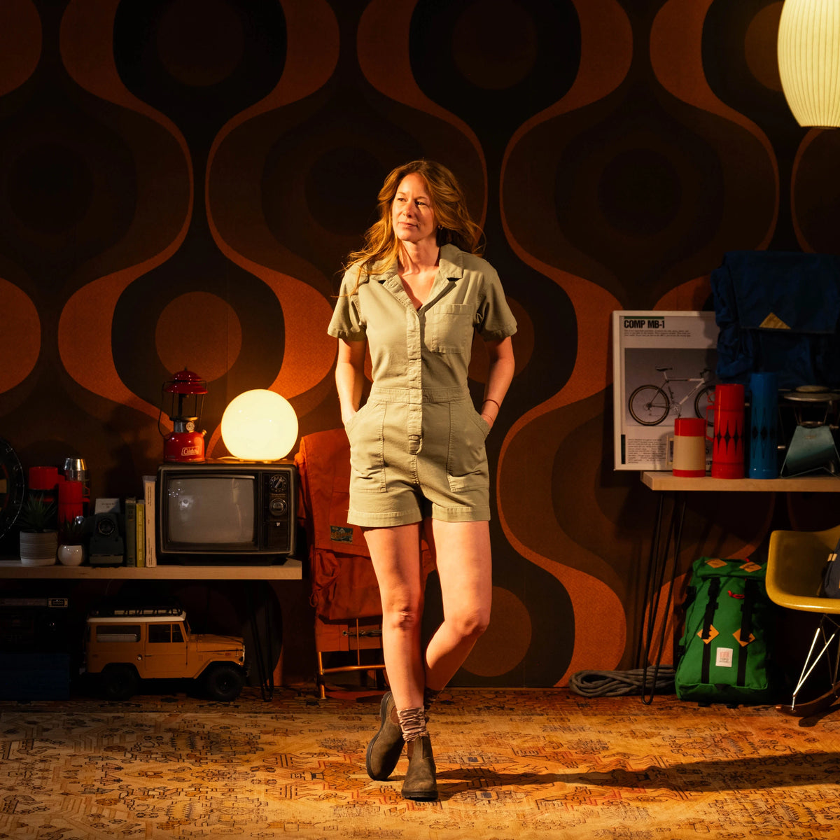 General lookbook image of Topo Designs Dirt Romper on model in studio setting shown in "Oil Green"